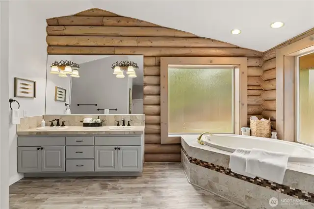 The primary bathroom boasts a double sink vanity, a spacious soaking tub, a separate shower area, and a large walk-in closet.