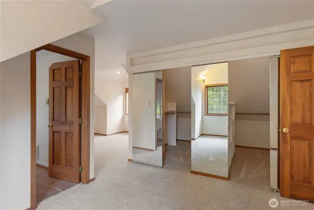Primary bedroom has a dressing area with closets and space for dresser.  Bed area is separated by design.