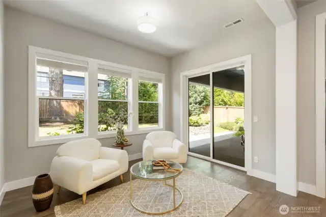 Just off the open-concept kitchen, this light-filled sitting room offers a cozy spot for morning coffee or casual conversation. Large windows and sliding glass doors frame the lush backyard, blending indoor comfort with outdoor serenity.