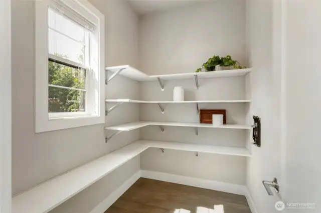 This spacious walk-in pantry offers generous open shelving and natural light, making it as functional as it is inviting. Perfectly positioned off the kitchen, it keeps everyday essentials organized and easily accessible.