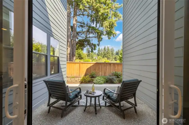 Directly off the formal dining room, this second patio offers a peaceful escape for after-dinner drinks or quiet morning coffee. Framed by lush landscaping and mature evergreens, it's a private retreat that seamlessly extends the living space outdoors.