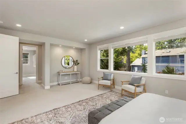 From this angle, the expansive primary suite reveals a cozy reading nook and a sunlit path leading to the luxurious en suite bath and walk-in closet. Clean lines, recessed lighting, and oversized windows create a tranquil, elevated space designed for everyday indulgence.