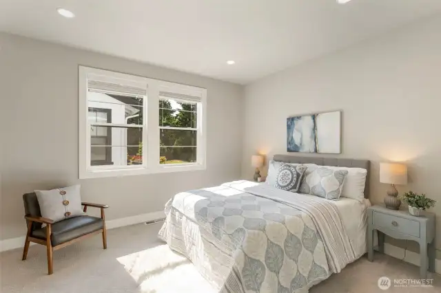 This upstairs spare bedroom is bright and welcoming, with large windows that invite in natural light and views of the landscaped yard. Neutral tones and plush carpeting create a cozy, restful space—ideal for guests, family, or a stylish home office.