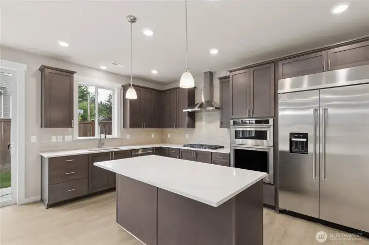 Large center island with quartz counters and loads of cabinets. Photo is representational. Actual home is under construction and finishes and colors will vary. See site agent for details.