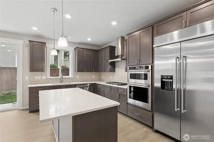 Large center island with quartz counters and loads of cabinets. Photo is representational. Actual home is under construction and finishes and colors will vary. See site agent for details.