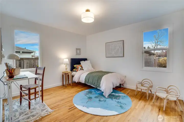 Bright and cheerful second bedroom with gleaming refinished hardwood floors, two large windows flooding the room with natural light, fresh paint, and a modern ceiling fixture. Plenty of space for a bed, desk, and play area – perfect as a guest room, home office, or kids’ room. Fully updated and move-in ready.