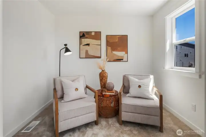 Primary Suite Sitting Nook: A dedicated sitting nook within the primary suite creates an inviting retreat, ideal for quiet mornings or evening relaxation. Sunlight streams through the window, highlighting the versatility of this bonus space. Staged photos are of the model home of the same floorplan within the Foxmoore community and are for visualization purposes only. Colors, finishes, and layout can and will vary.