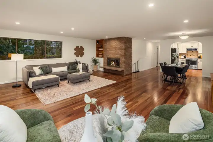 Warmth meets modern design. The spacious open-concept living room features rich hardwood floors and a signature brick fireplace that serves as the heart of the home.
