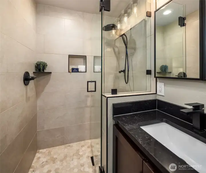 Detail-oriented design. From the honeycomb tile flooring to the rainfall showerhead and recessed niche, no expense was spared in this bathroom remodel.