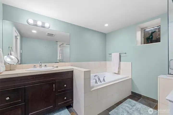 Primary bathroom with soaking tub, travertine enclosure.