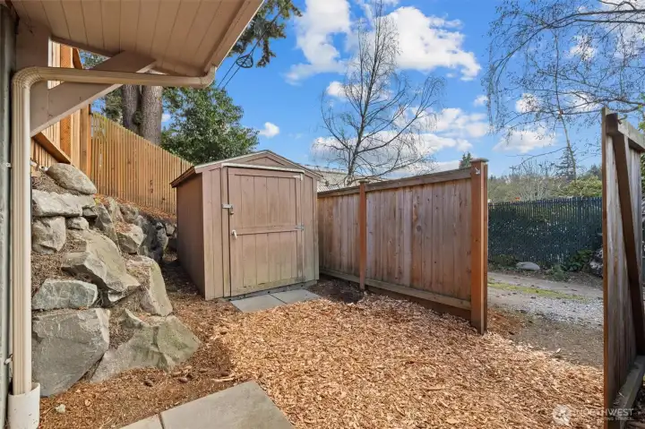 Fenced area at ground level off the media room. Here you see the gate opened, and useful storage shed. The entire back yard and this side of the property is fully fenced.  Alley access.