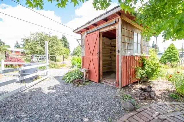 Rustic, rare wooden garden shed next to raised beds and garden