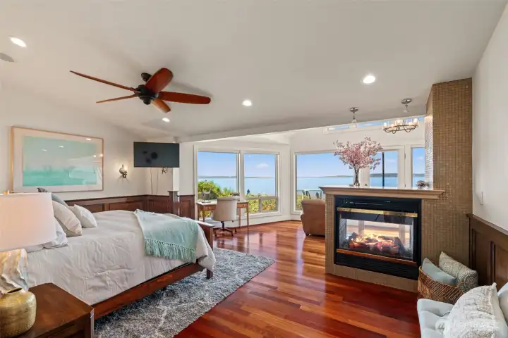The primary suite captures sweeping Puget Sound views from every angle, with a tiled gas fireplace, vaulted ceilings, and rich flooring creating a true retreat. The primary suite captures sweeping Puget Sound views from every angle, with a tiled gas fireplace, vaulted ceilings, and rich flooring creating a true retreat.