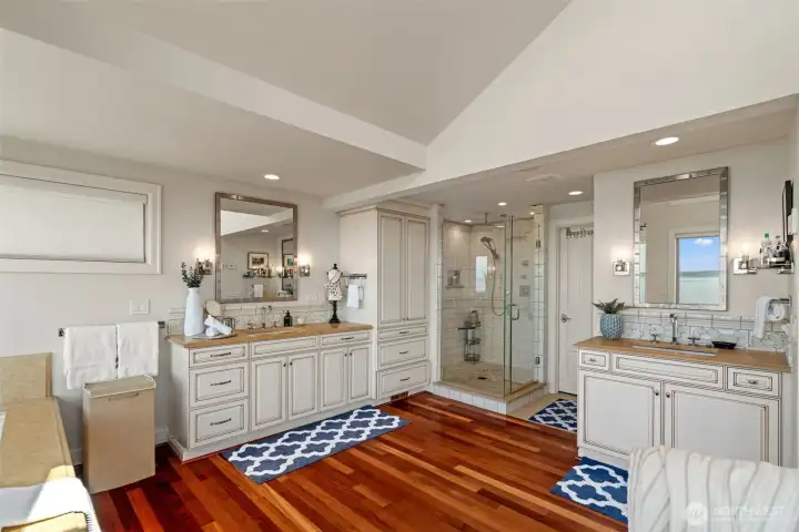Spa-like primary bath features dual vanities, a glass-enclosed walk-in shower, and abundant custom cabinetry. Spa-like primary bath features dual vanities, a glass-enclosed walk-in shower, and abundant custom cabinetry.