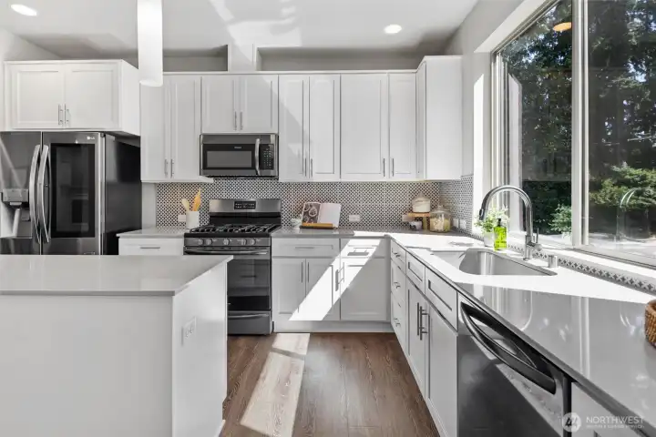 Large windows frame peaceful greenery views while filling the kitchen with natural light. Large windows frame peaceful greenery views while filling the kitchen with natural light.