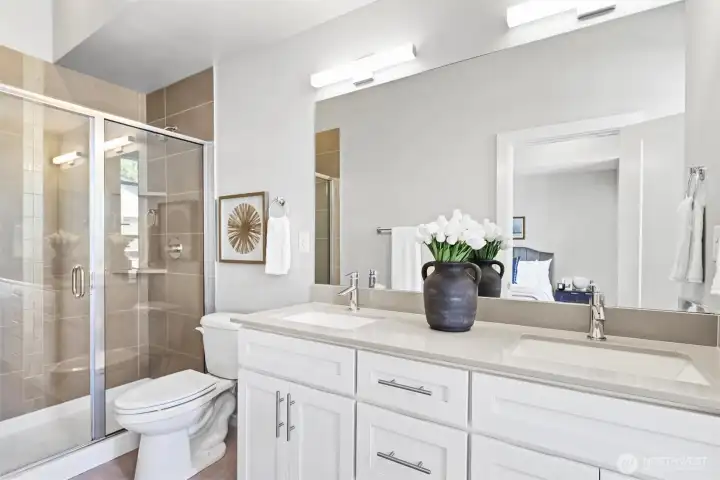 Spa-inspired primary bath with dual vanities, quartz counters, and a large glass-enclosed shower. Spa-inspired primary bath with dual vanities, quartz counters, and a large glass-enclosed shower.