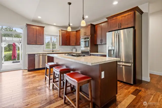 Prepare a feast in your dream Kitchen. Pendant lighting above island counter with gas cooktop and eating bar. Crown molding tops the tall cabinetry. Granite counters with full back splash. Stainless appliances.