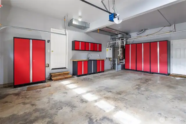 Three-car garage with newer furnace and tankless water heater.  To the right of the door are some built-in cabinets with work space and extra sink.