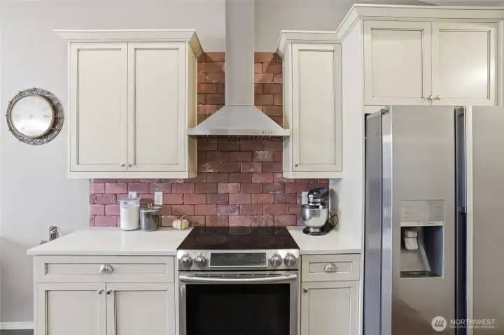 Stainless steel range, vent hood with custom brick backsplash