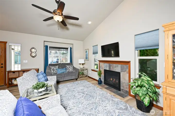 Living room with LVP flooring, vaulted ceilings, and a gas fireplace.