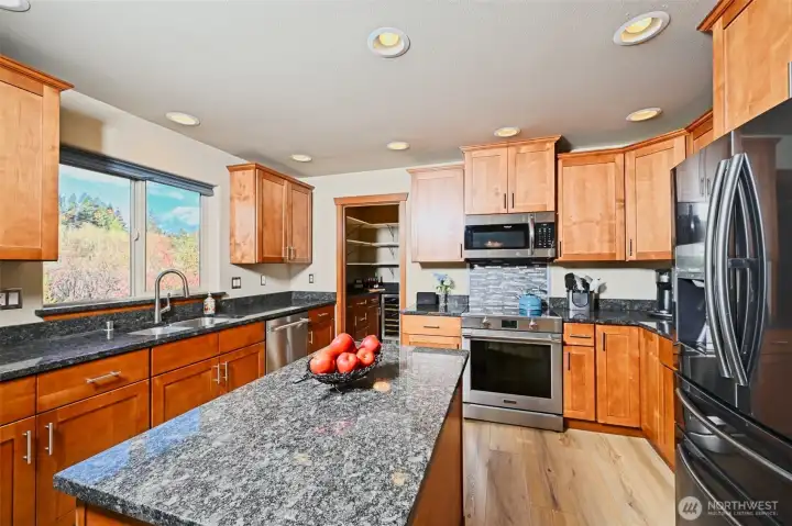 Expansive Chef's kitchen with beautiful wood cabinets, granite countertops, newer stainless steel appliances, an island for more prep space and a butler's pantry.