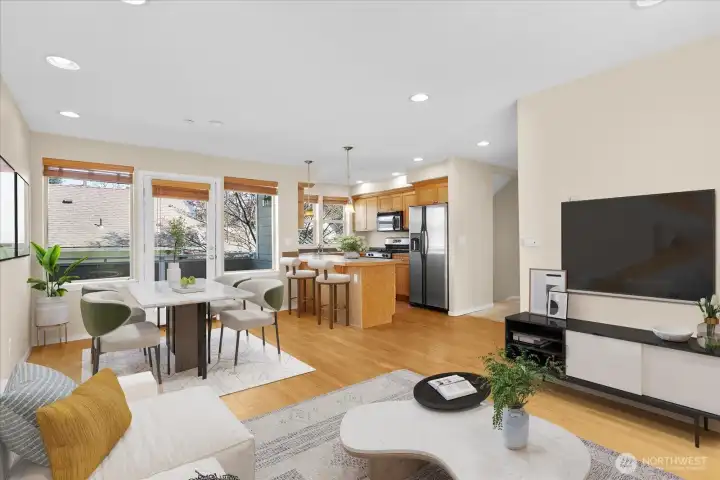 Virtually staged living, dining, and kitchen space with wood flooring, modern furnishings, and large windows with blinds.