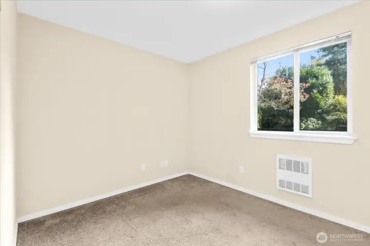Bedroom with carpeted flooring, beige walls, and a window providing natural light.