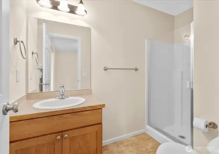 Private bathroom with single-sink vanity, wall mirror, toilet, and glass-enclosed shower.