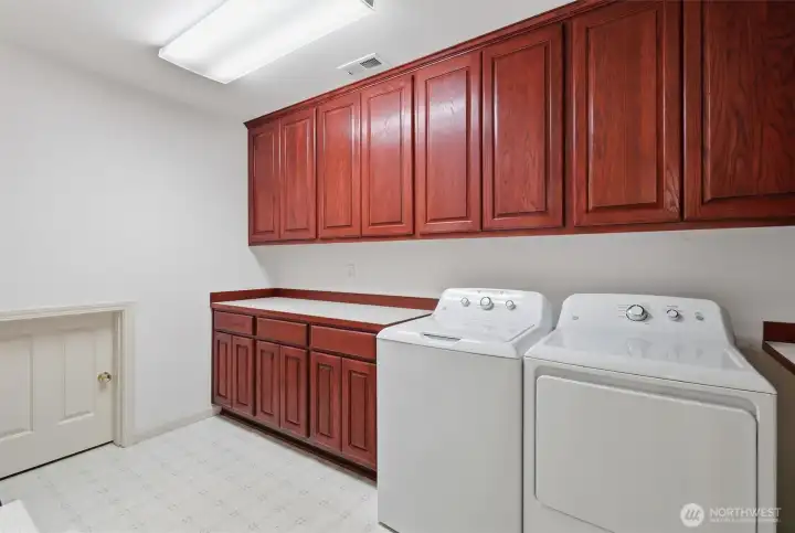 Utility room with folding counter, plenty of cabinets and the small door leads to wine racks and additional storage.