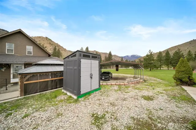Shed with 2-car carport and property in the background.