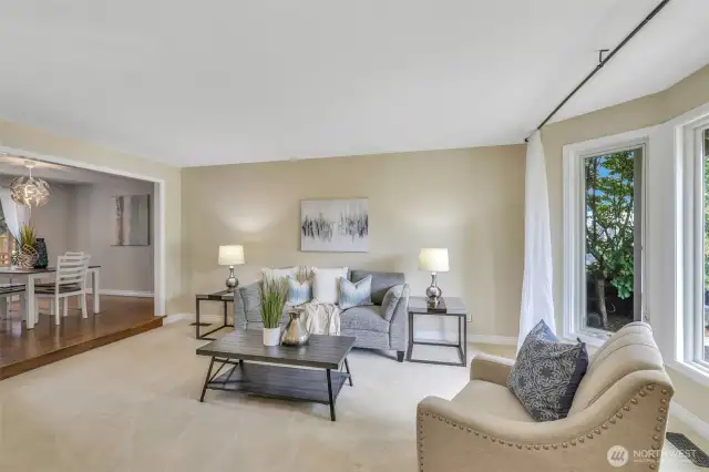 The light-filled living room offers a tranquil retreat with expansive windows that frame the lush front yard. Neutral tones and plush carpeting create a calming space ready for personalization.