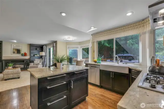 The updated kitchen is both functional and elegant, featuring slab granite counters, a farmhouse-style sink, and generous natural light from oversized windows that overlook the private backyard.