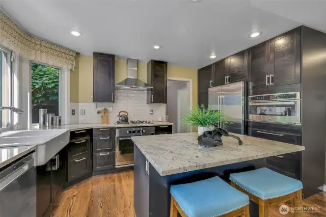 From every angle, the kitchen is a chef’s delight—complete with modern venting, built-in ovens, and expansive countertop space, all seamlessly connected to the dining and living areas.