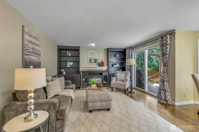 The adjacent family room is anchored by an electric fireplace with custom built-ins, offering a welcoming setting for gatherings and quiet nights in. Sliding glass doors provide direct access to the deck.