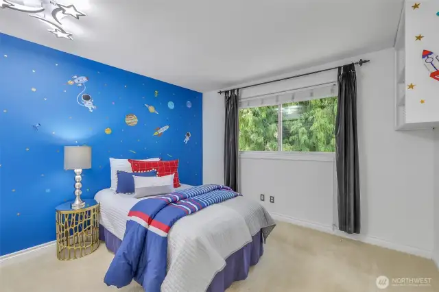 One of the secondary bedrooms enjoys a large window with backyard views and a playful wall design, perfect for customizing to your lifestyle needs—whether for rest, study, or creative play.