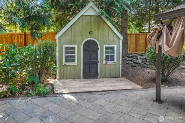 A charming playhouse adds a whimsical touch and additional functionality to the backyard—a delightful feature for imaginative play or garden storage.