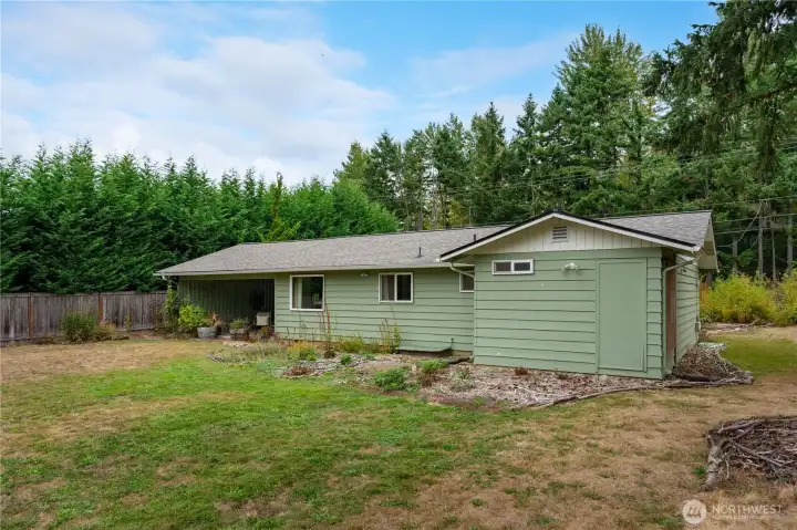 Back of the home with glimpse of open yard space.