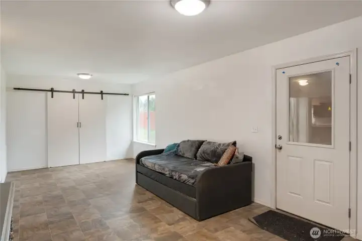 This family room can be a sitting room or livinig room if you opt to use this wing of the home as a 'mother-in-law apartment or ADU. It features a private entry, its own full bath, and the kitchen and utilities are stubbed off in the space behind the barn door and non-load-bearing wall at the rear. The door to the right access the outside including to the dog-run or to the parking area. There is also a separate and private bedroom included with this space.