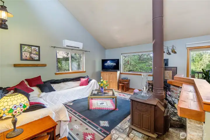 Vaulted ceilings, warm wood accents, and a cozy freestanding stove create an inviting great room designed for gathering and relaxation.