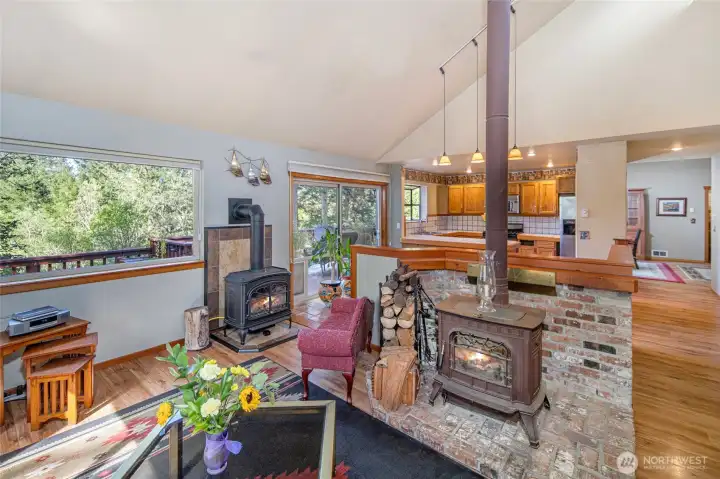 Dual wood stoves and expansive windows make the main living area both cozy and inviting, with year-round comfort and beautiful forest views.