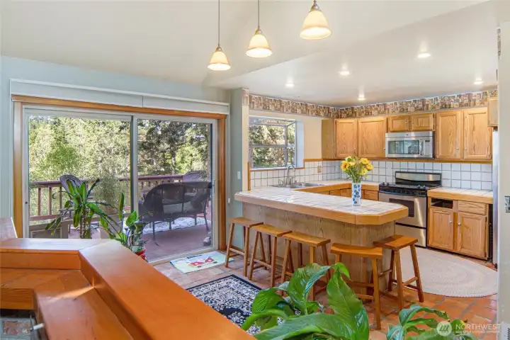 Open-concept kitchen features generous counter space, bar seating, stainless appliances, and seamless access to the outdoor deck for easy entertaining.