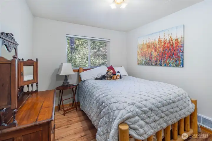 Comfortable guest bedroom with peaceful wooded views and warm natural light, offering privacy and flexibility for visitors or home office use.