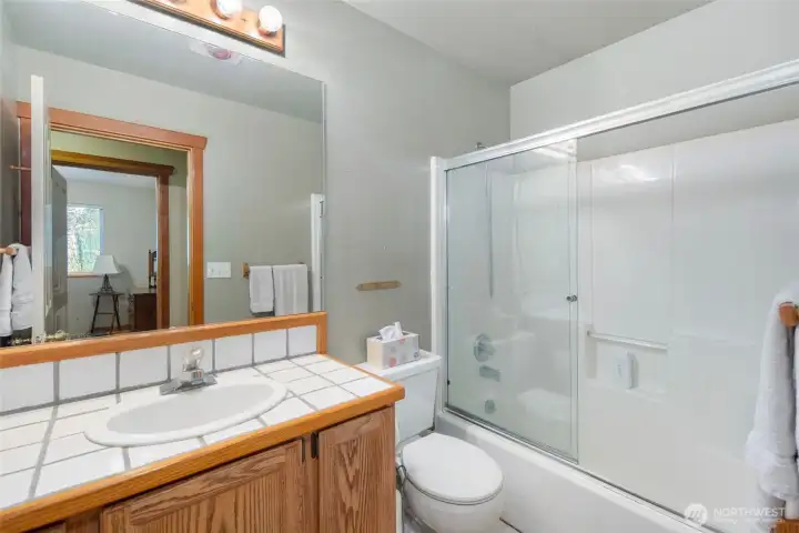 Full guest bath with clean finishes, tiled vanity, and tub/shower combination designed for everyday comfort and convenience.