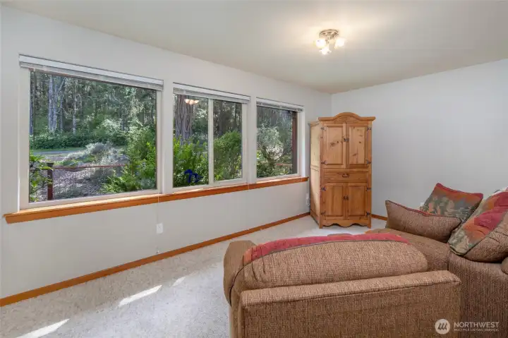 Large picture windows bring in natural light and peaceful garden views, creating a bright and comfortable guest or flex room.