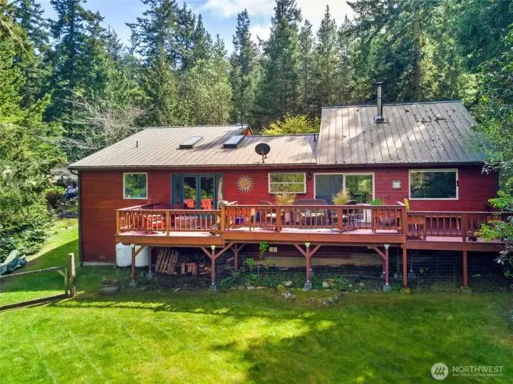 Bright and sunny backyard with generous deck and wooded privacy provides a perfect balance of indoor-outdoor living on San Juan Island.