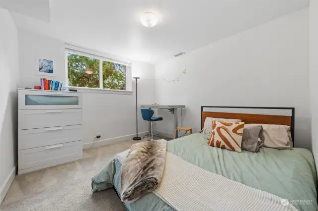 On the lower level, you'll find Bedroom Four, it offers a bright and warm space with a large window and a functional layout. Soft carpeting and neutral tones making it comfortable.