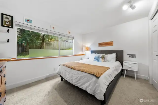 On the lower level, you'll find Bedroom Three, it features a spacious layout, a large window with backyard views, and a generous closet. Notice the window ledge that offers space for decor.