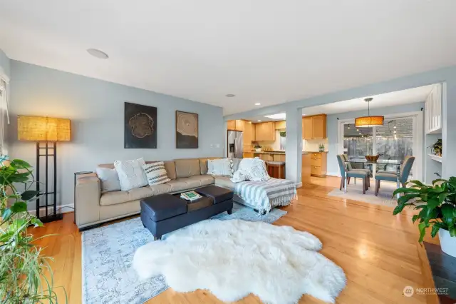 The living room flows effortlessly into the dining area and kitchen, creating a perfect space for entertaining. Warm hardwood floors and soft-toned walls enhance the inviting atmosphere.