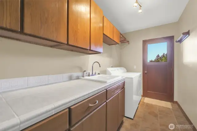 Conveniently located laundry room next to garage features deep sink, tile counter and plenty of storage.  Door leads to side of house.