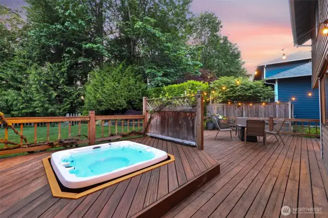 Hot tub at the heart of the space surrounded by fencing and grapevine trellis.